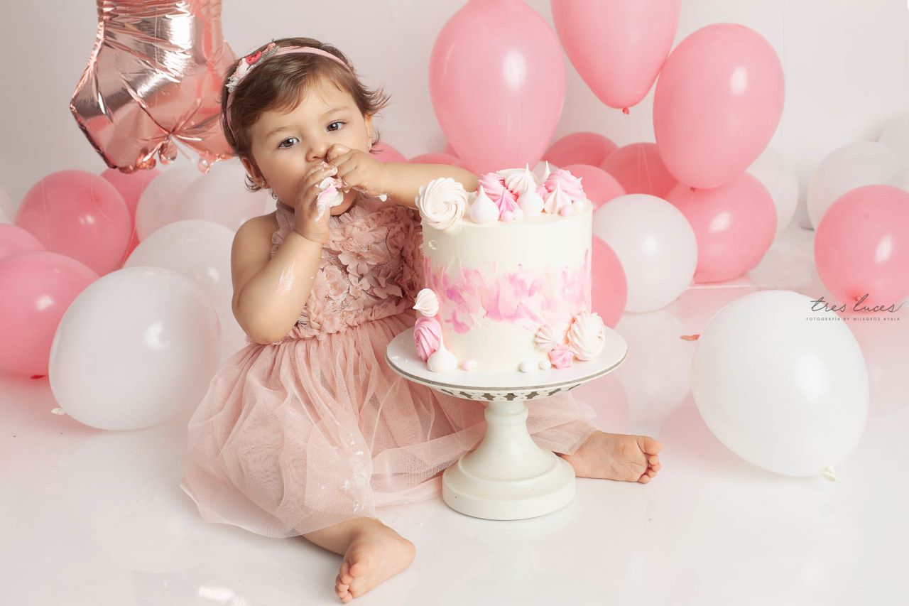 Bebé de 1 año en un estudio fotográfico con un pastel y globos