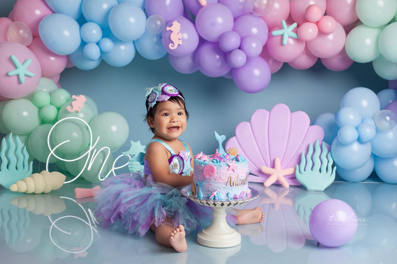 Bebé de 1 año en un estudio fotográfico con un pastel y globos